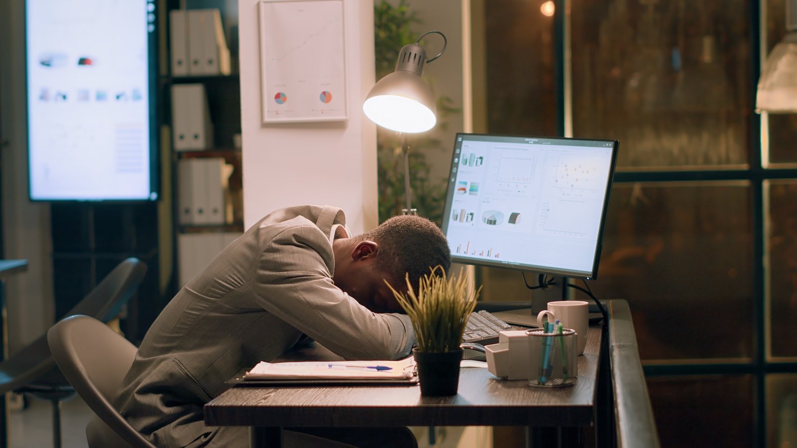 Un homme d'affaires afro-américain surchargé de chaise de bureau tout en travaillant pendant la nuit au bureau. 