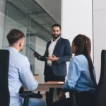 Boss masculin du Moyen-Orient avec un rapport de paperasse en coaching et enseignement des employés professionnels pendant la présentation de séminaire à l'intérieur du bureau
